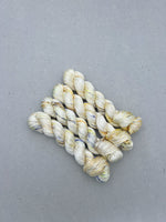 Three skeins of cream-colored yarn on a gray background