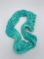 Turquoise yarn skein on a light gray background