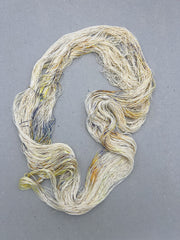 Three skeins of cream-colored yarn with speckles on a gray surface