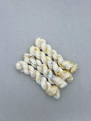 Three skeins of cream-colored yarn on a gray background